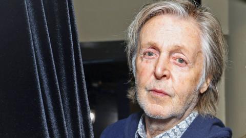 Headshot of musician Paul McCartney, wearing blue blazer and open-necked shirt, taken in 2023