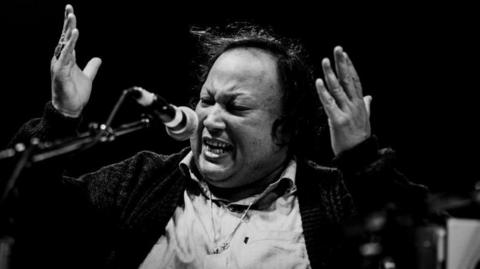 A black and white photo of Nusrat Fateh Ali Khan singing