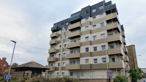 A picture of Nova House with cream and brown cladding. It is a residential tower block with seven floors. 