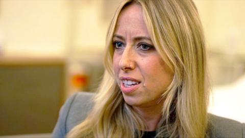 Head and shoulders of Catrin Nye - a woman with long blonde hair wearing a grey blazer.