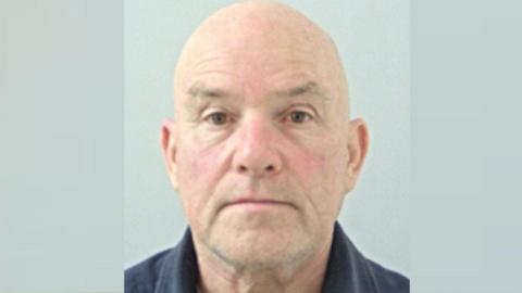 A mugshot of Robert Crompton, a bald man wearing a black shirt.
