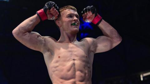 Paul Hughes flexes his muscles as he celebrates