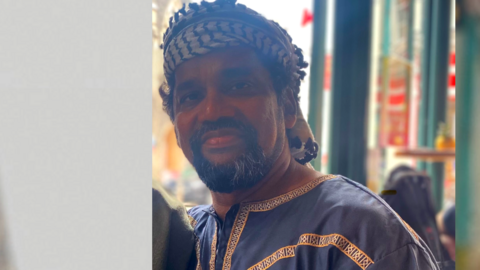 Muslim Imam in traditional dress looks at the camera