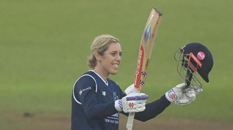 Georgia Adams raises her bat to acknowledge her century for Hampshire