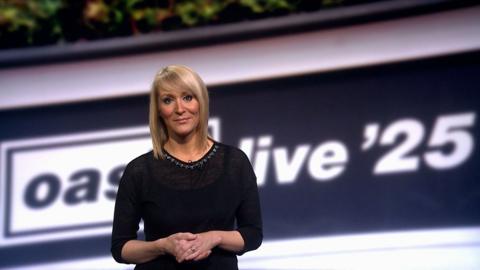 Kirsteen MacDonald stands in front of a banner saying Oasis live '25