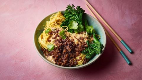 Mince, noodles and green veg in a bowl with a pair of chopsticks laying alongside