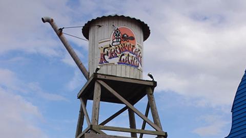 A wild west style water tower on a high wooden platform saying Frontierland in red and yellow