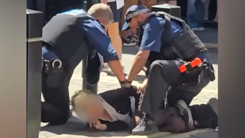 Picture of a woman being arrested by two police officers (suspect's face blurred)