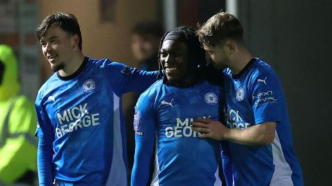 Abraham Odoh (centre) celebrates a goal with two Peterborough team-mates