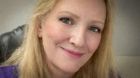 A photo of a blonde woman looking at the camera