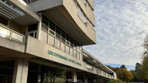 A large concrete building with a green lettered county council sign on the front