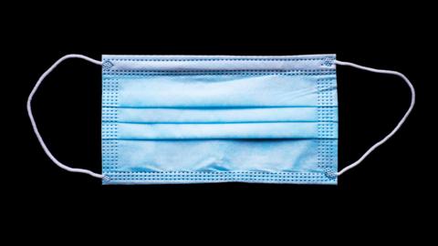 A close-up of a blue standard face-mask against a black background.