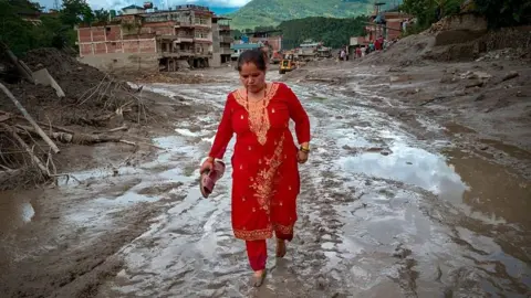  A resident walks along a muddy road following flash floods on August 27, 2026 in Trishuli, Nepal. A sudden flood swept through the Bhote Koshi River basin in northern Rasuwa on August 26,