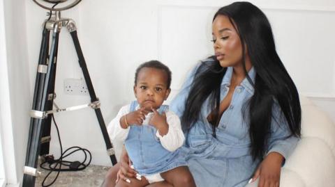 Tawana Musvaburi poses with her child. They both wear light blue denim.