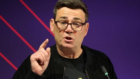 Andy Burnham giving a speech at a conference in Leeds.