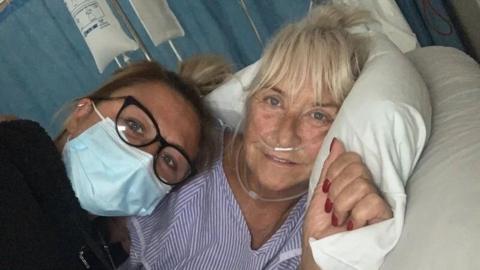 Two women lying on a hospital bed. 