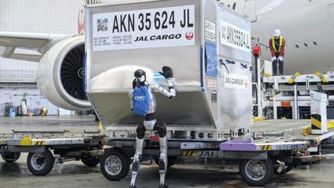 A robot pushes a cargo truck in Haneda airport.