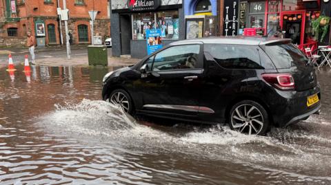 A black car driving through flood waters