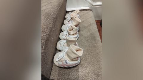 Three pairs of identical baby shoes and socks lined up along a carpeted stair 