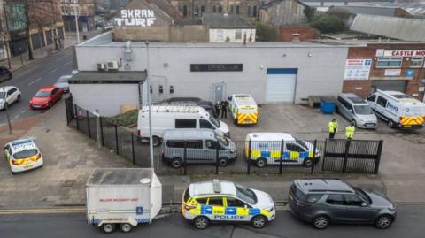 A drone picture showing a number of police vehicles, including one towing a "Major Incident Unit" trailer, outside the premises of Legacy Independent Funeral Directors in Hull