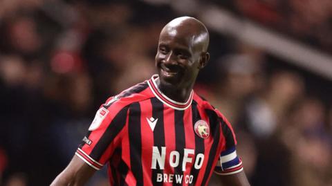 Walsall striker Albert Adomah smiling at fans while playing in a match 