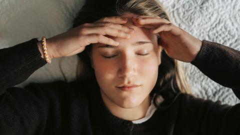 Directly above shot of stressed young woman lying on bed - stock photo