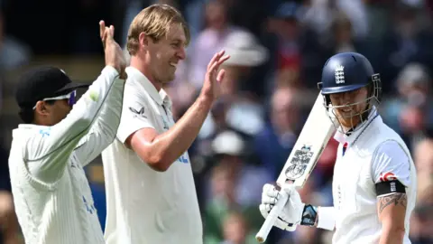 New Zealand players celebrate a wicket as England captain Ben Stokes (right) walks off after being dismissed