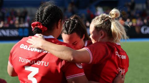 Sisilia Tuipulotu, Courtney Keight and Kelsey Jones hug on the field