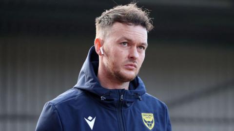 Josh McEachran looks on while wearing his Oxford United tracksuit 