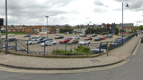 A street view image of a large car park taken from a road in the corner