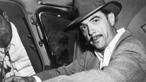 Howard Hughes sits in the back of a car