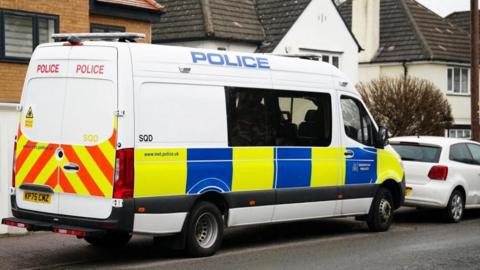 A police van parked on a road in Watford. There are detached houses behind it.