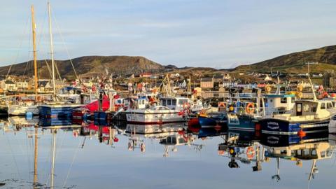 Coloured boats on the water with mountains and grey blue sky behind