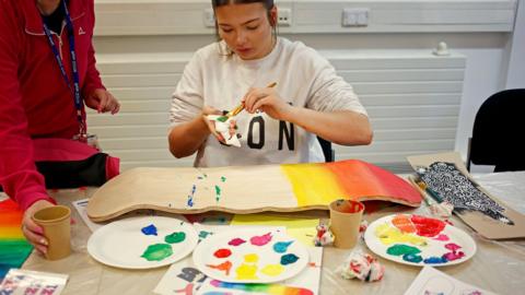 Student painting a skateboard for the project