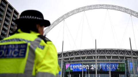 A police officer stands on duty with Wembley stadium in the background during the UEFA Champions League 2023/24 final match between Borussia Dortmund v Real Madrid CF at Wembley Stadium on May 31, 2024 in London