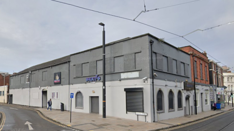 Beet's Lounge a white and grey painted building with black shutters over the doors and windows