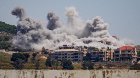 View from afar of large plumes of smoke rising over buildings struck by Israel in the Nabatieh area, southern Lebanon.