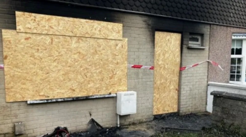 A house pictured boarded up with fie damage 