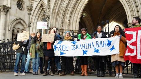 Protesters outside the The Royal Courts Of Justice in London, some are holding a banner which reads Free Ibrahima Bah and another holds a sign which reads Justice for Ibrahima