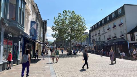 A town centre shopping street with people milling about.