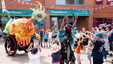 Children in Beverley watch a performance of giant dragon on a wheeled cart
