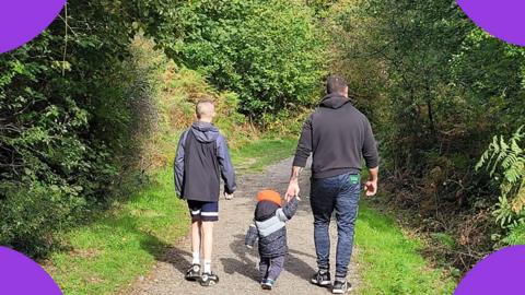 A dad is walking with his two children