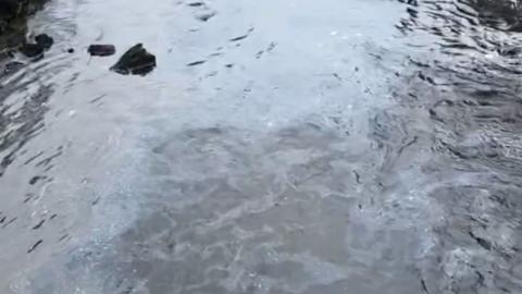 Fuel spill in a river in Perthshire, the water looks oily with a white film on it in places