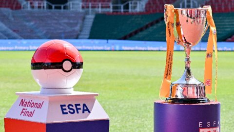 Photo of a large Poké Ball and a ESFA Cup on a football pitch.