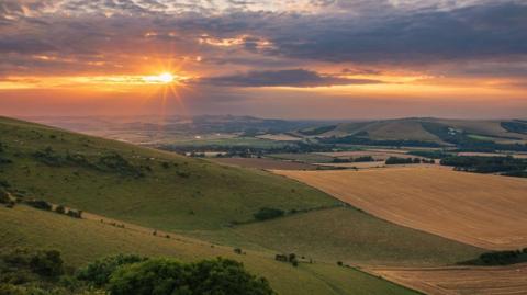 Sweeping green hills as the sun sets.