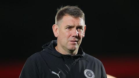 Manager Dave Challinor wears a serious expression on the touchline for Stockport County