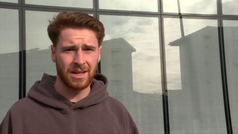 A young man with a short beard looking towards the camera