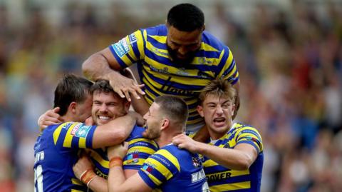 Joe Philbin is mobbed by Warrington Wolves team-mates after scoring a try against Hull KR.