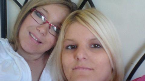 Bethan Callaghan (right) picture with her sister Chloe Callaghan. Chloe has dark blonde hair with a side fringe and wears pink rectangle rimmed glasses. She has blue eyes and smiles at the camera. Bethan has brown eyes and bright blonde hair. She looks directly at the lens and smiles. 