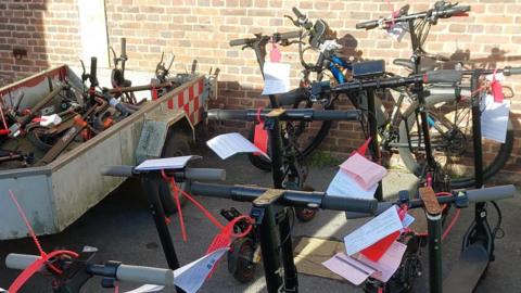 A collection of e-scooters with tags on their handlebars